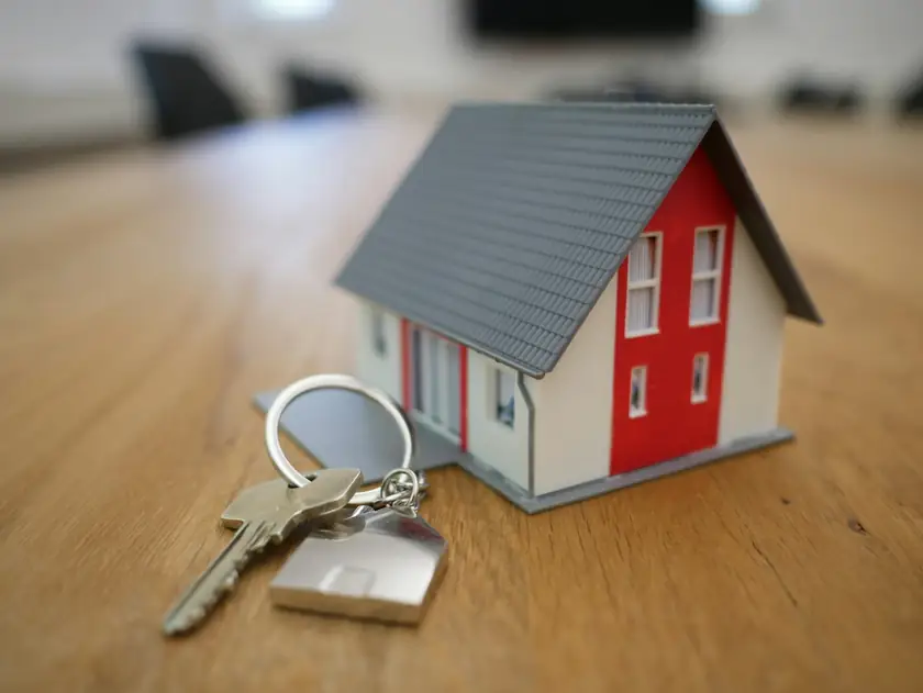 Miniatura de casa e chaves sobre uma mesa de madeira