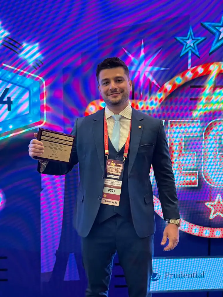 Renan Hypolito no palco da convenção PTC 2024, segurando a placa de premiação